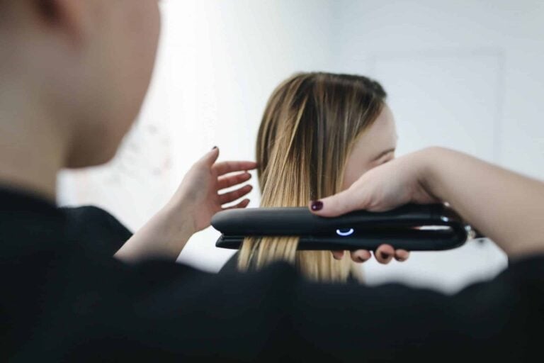 Une coiffeuse à domicile lisse les cheveux d'une femme.